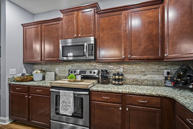 kitchen featuring decorative backsplash, hardwood / wood-style floors, stainless steel appliances, and light stone countertops