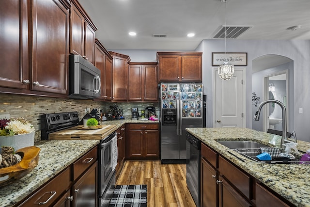 kitchen with pendant lighting, sink, light hardwood / wood-style flooring, tasteful backsplash, and stainless steel appliances