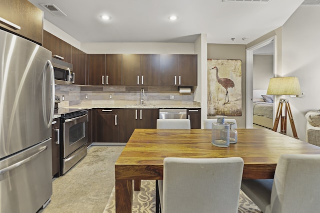 kitchen featuring dark brown cabinets, sink, decorative backsplash, and stainless steel appliances