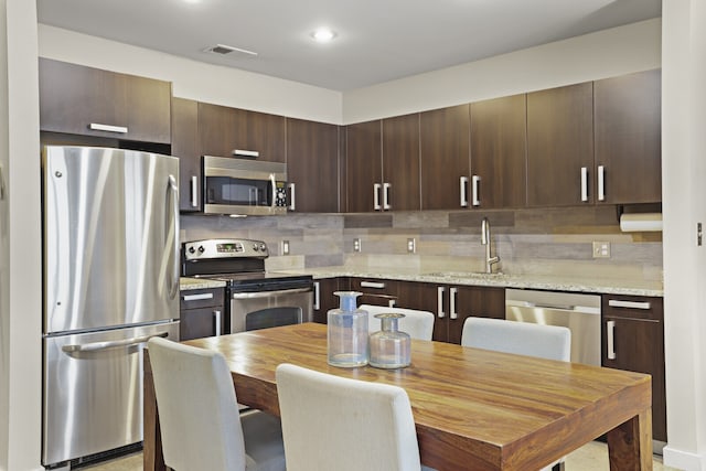 kitchen featuring decorative backsplash, dark brown cabinetry, stainless steel appliances, and sink