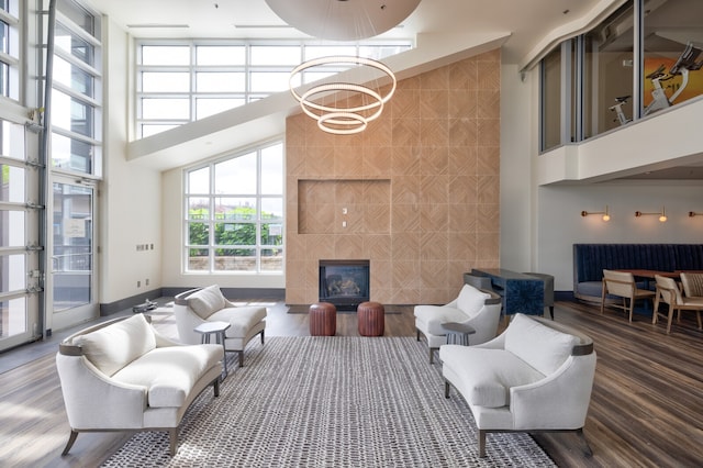 living room with a high ceiling, a tiled fireplace, and wood-type flooring