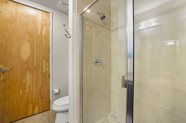 bathroom with tile patterned floors, toilet, and a shower with shower door