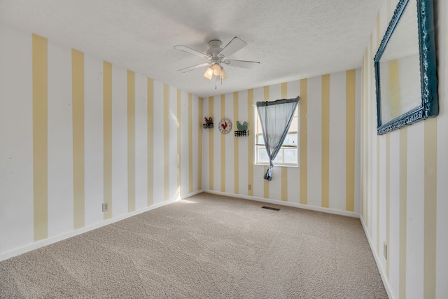 empty room with carpet, ceiling fan, and a textured ceiling