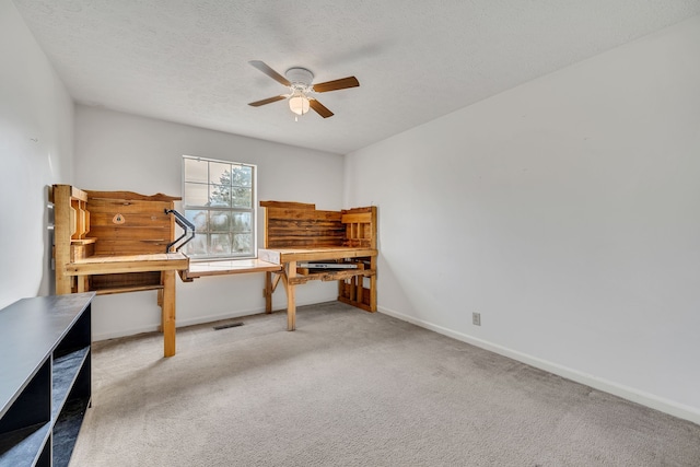 carpeted home office with ceiling fan and a textured ceiling