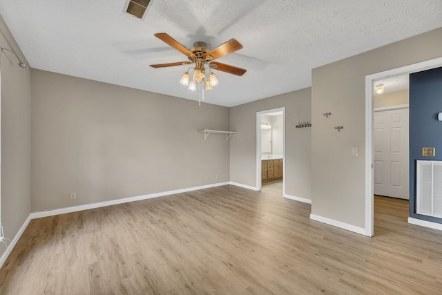 unfurnished room with a textured ceiling, light wood-type flooring, and ceiling fan