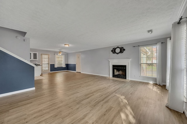 unfurnished living room with a textured ceiling, light hardwood / wood-style floors, ceiling fan, and ornamental molding