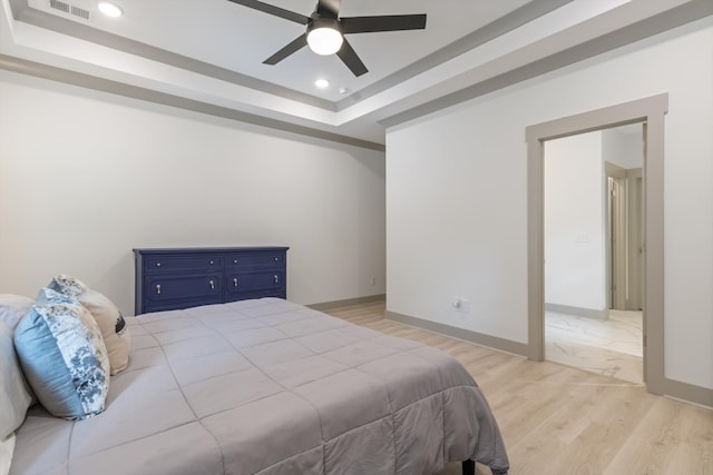 bedroom with a tray ceiling, light hardwood / wood-style flooring, and ceiling fan