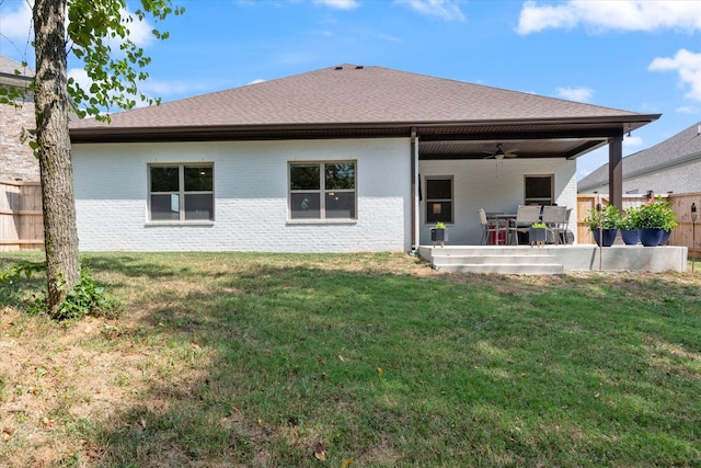 back of property with ceiling fan, a patio area, and a yard