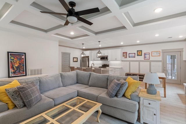 living room featuring beamed ceiling, light hardwood / wood-style floors, ceiling fan, and coffered ceiling