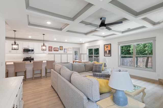 living room with beamed ceiling, ceiling fan with notable chandelier, light hardwood / wood-style floors, and coffered ceiling