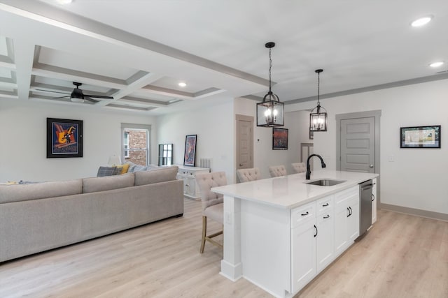 kitchen with white cabinets, sink, hanging light fixtures, an island with sink, and light hardwood / wood-style floors