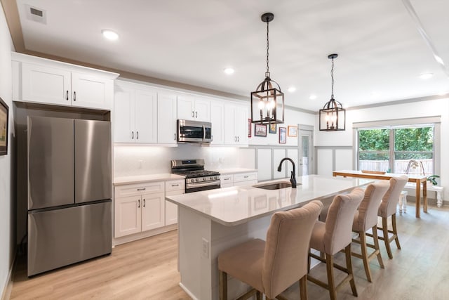 kitchen featuring a center island with sink, light hardwood / wood-style floors, white cabinetry, and stainless steel appliances