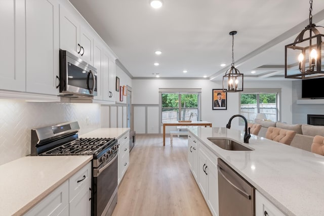 kitchen with decorative light fixtures, a healthy amount of sunlight, sink, and appliances with stainless steel finishes