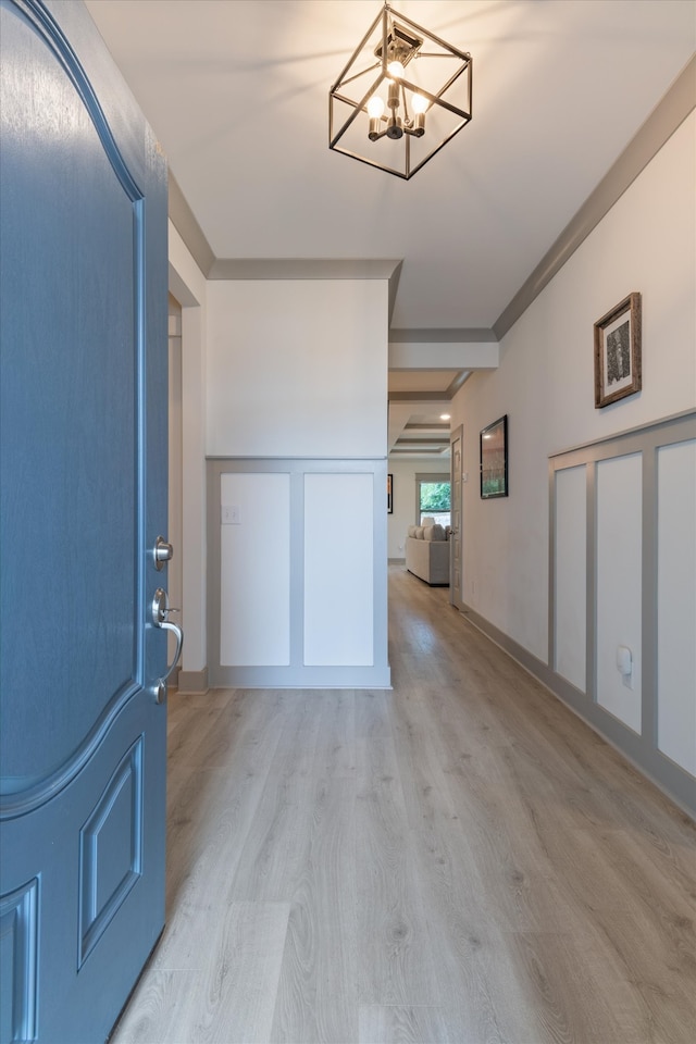 entryway with ornamental molding, light hardwood / wood-style floors, and an inviting chandelier