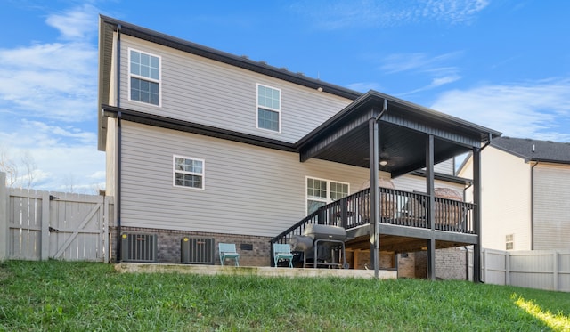 back of property with a wooden deck, a yard, and cooling unit