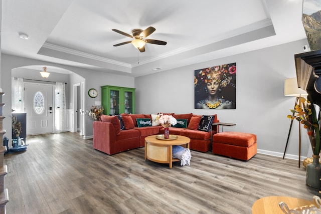 living room featuring crown molding, a tray ceiling, and wood-type flooring