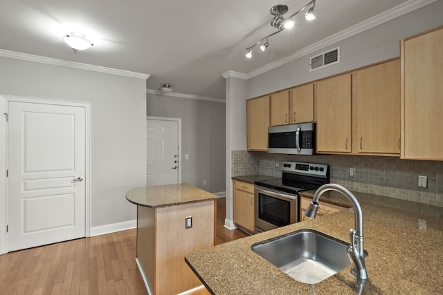 kitchen featuring crown molding, sink, light wood-type flooring, an island with sink, and appliances with stainless steel finishes