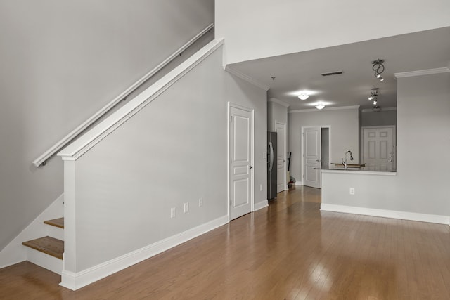 unfurnished living room with crown molding, sink, and wood-type flooring