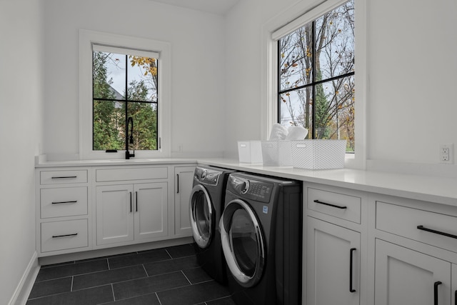 laundry area featuring washer and dryer, dark tile patterned floors, cabinets, and sink