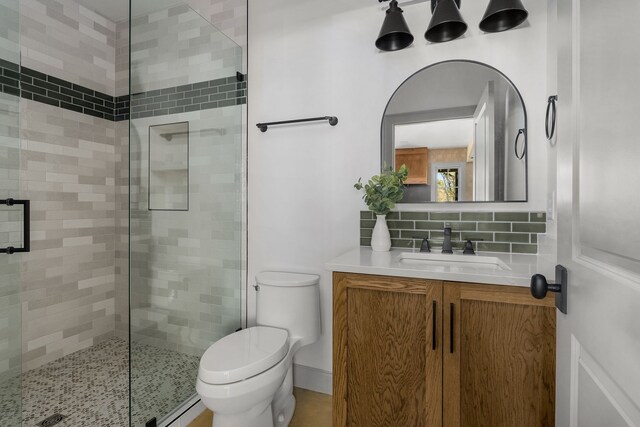 bathroom featuring an enclosed shower, decorative backsplash, toilet, and vanity