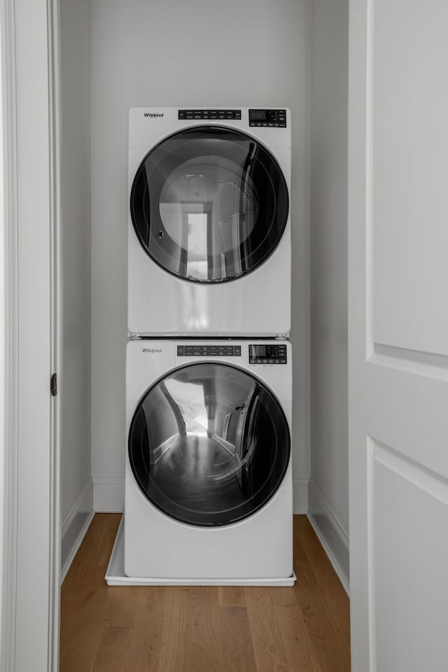 laundry area with wood-type flooring and stacked washer and dryer