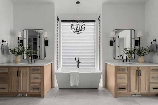 bathroom featuring tile patterned flooring, a washtub, vanity, and an inviting chandelier