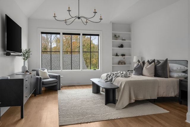 bedroom featuring vaulted ceiling, a notable chandelier, and hardwood / wood-style flooring