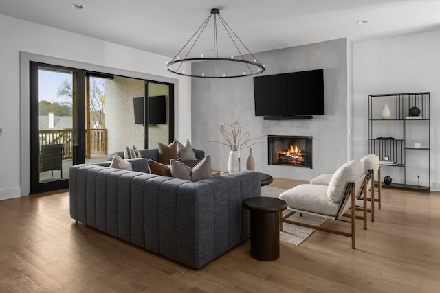 living room with hardwood / wood-style flooring, a fireplace, and an inviting chandelier