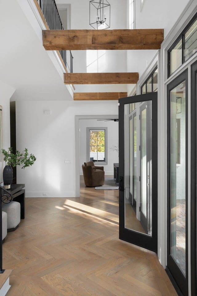 foyer entrance with a towering ceiling, french doors, and light parquet floors