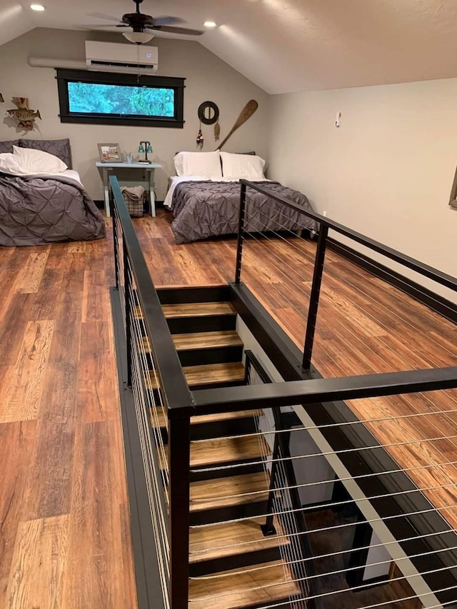 unfurnished bedroom with an AC wall unit, wood-type flooring, and lofted ceiling