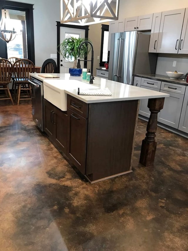 kitchen featuring a kitchen breakfast bar, gray cabinetry, stainless steel appliances, a kitchen island with sink, and sink