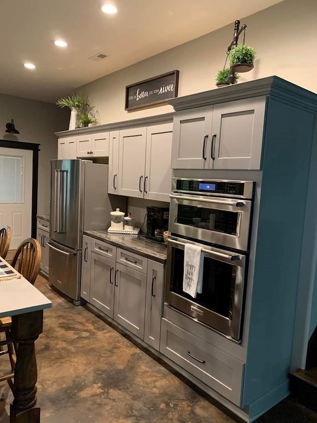 kitchen with gray cabinetry, stone counters, and stainless steel appliances