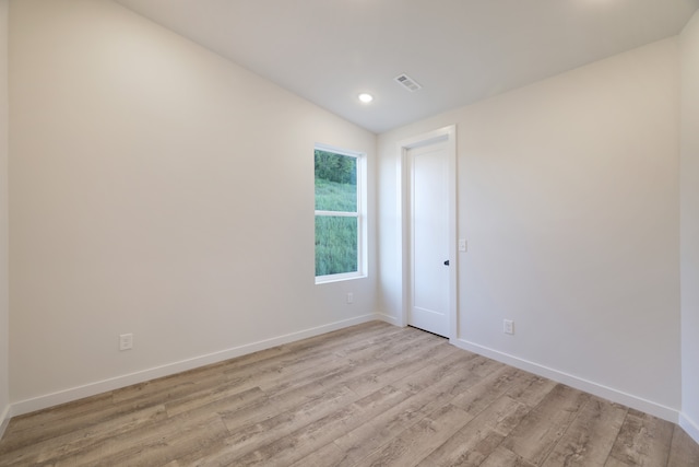 spare room with light wood-type flooring and lofted ceiling