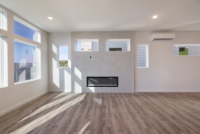 unfurnished living room with wood-type flooring and an AC wall unit