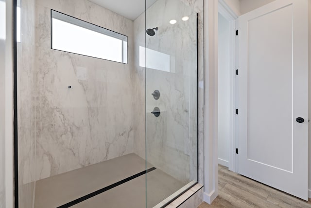 bathroom with tiled shower and wood-type flooring