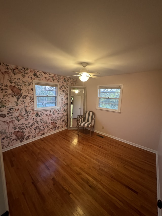 spare room featuring dark wood-type flooring, ceiling fan, and plenty of natural light