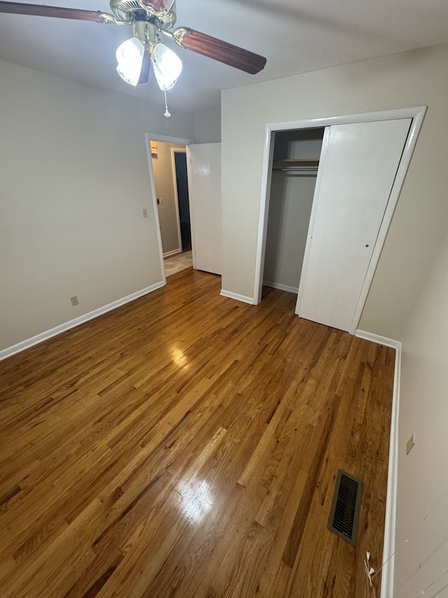 unfurnished bedroom with ceiling fan, wood-type flooring, and a closet