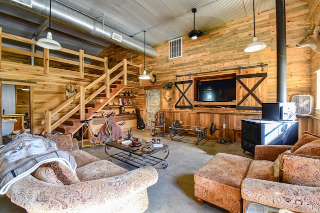 living room with wooden walls, a towering ceiling, concrete floors, and ceiling fan