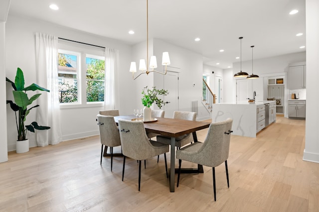 dining space with light wood-type flooring, sink, and a chandelier