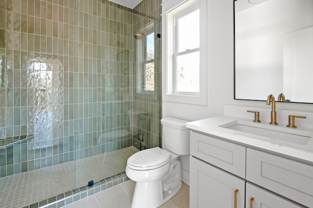 bathroom with a tile shower, a wealth of natural light, tile patterned flooring, and vanity