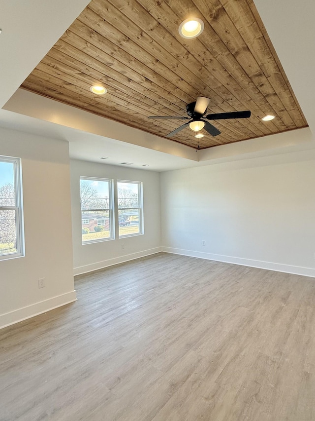 unfurnished room with light wood-type flooring, a tray ceiling, ceiling fan, and wood ceiling