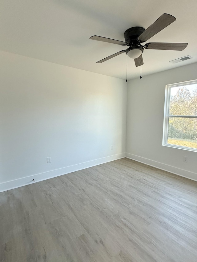 empty room with ceiling fan and light hardwood / wood-style flooring