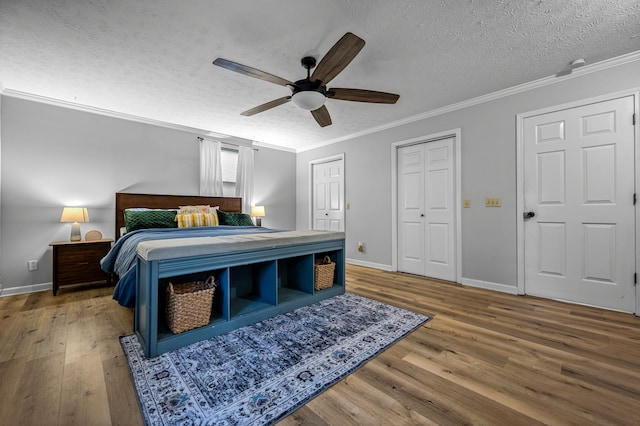 bedroom featuring hardwood / wood-style flooring, ornamental molding, a textured ceiling, and multiple closets