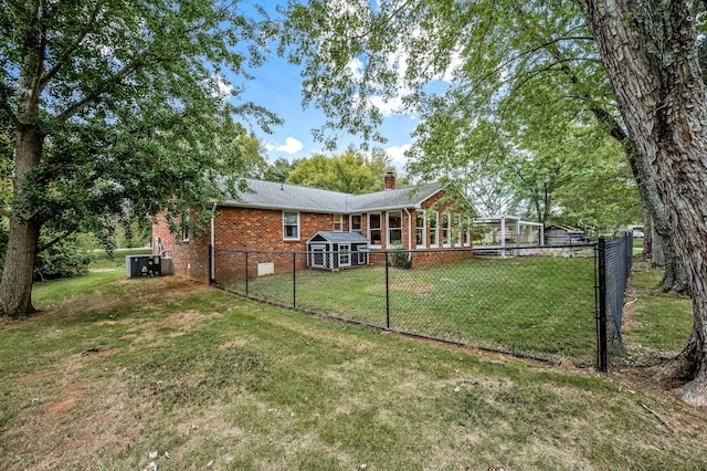 back of property with cooling unit, a shed, and a lawn