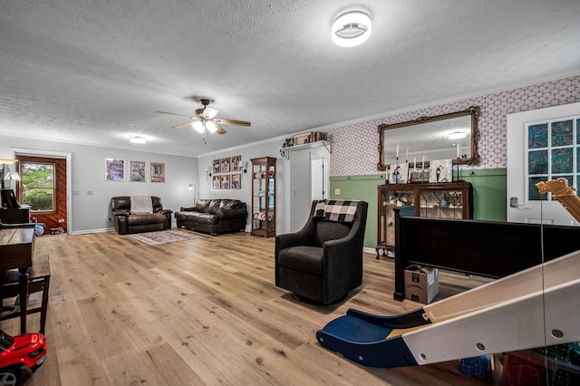 living room with ceiling fan, ornamental molding, wood-type flooring, and a textured ceiling