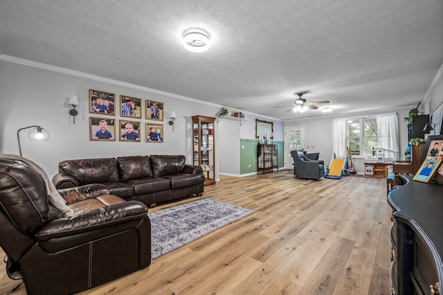 living room with ceiling fan, ornamental molding, light hardwood / wood-style floors, and a textured ceiling