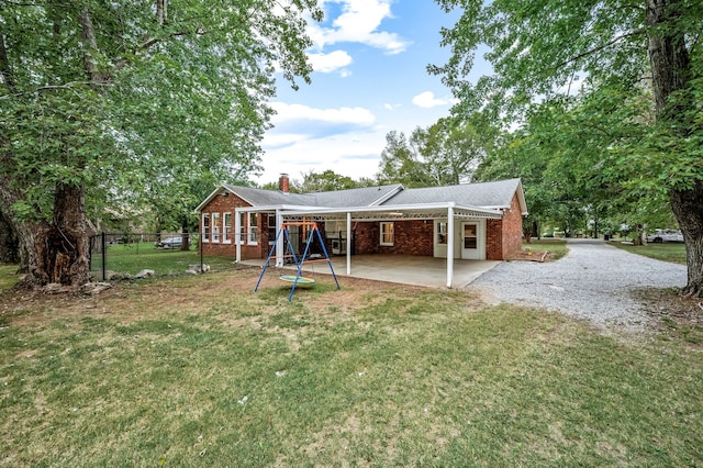 rear view of property featuring a patio area, a playground, and a lawn