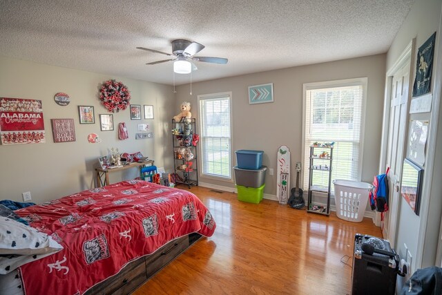 bedroom with wood-type flooring, a textured ceiling, and ceiling fan