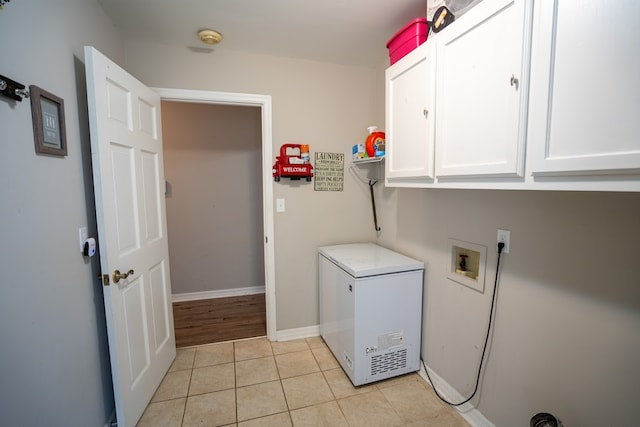 clothes washing area featuring hookup for a washing machine, light tile patterned flooring, and cabinets