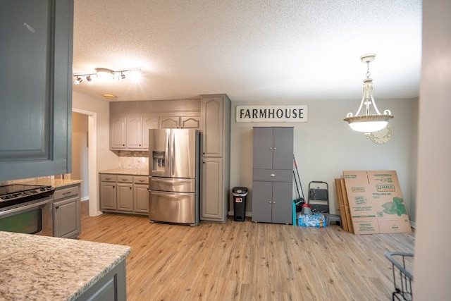 kitchen featuring gray cabinetry, light hardwood / wood-style flooring, pendant lighting, a textured ceiling, and appliances with stainless steel finishes